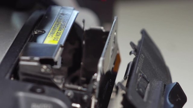 Hand placing a Mini DV tape into a camera deck in extreme slow motion.
