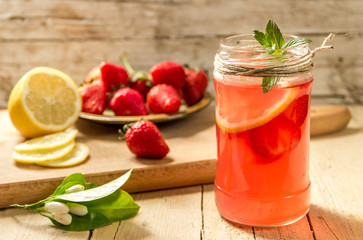 Fototapeta na wymiar Освежающий, холодный напиток с клубникой, лимоном и мятой на деревянном фоне