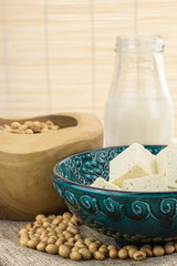Tofu cut into cubes, soybeans in bowls and soy milk