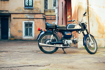 Fototapeta na wymiar Old blue with chrome motorcycle parked near the old buildings