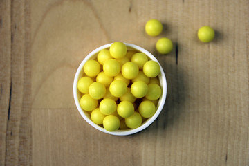 handful of many round yellow vitamin C dragee pills closeup on w