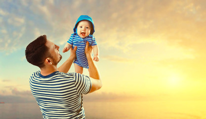 happy family father and baby son on beach by sea at sunset