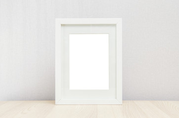 blank white picture frame on the wall and the table wood