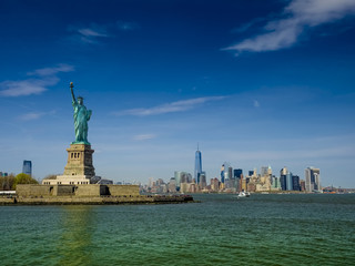 Statue of Liberty on a sunny day, Manhatten in the background. This is a photo-montage, because the statue faces to the viewer!