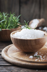 White salt and green rosemary on the wooden table