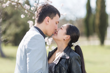 Asian girl and european guy kissing against of blossoming almond