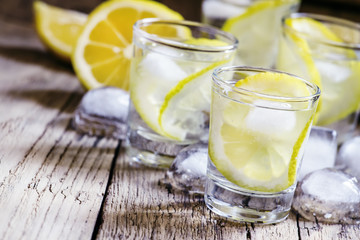 Obraz na płótnie Canvas Lemon vodka with ice, vintage wooden background, selective focus