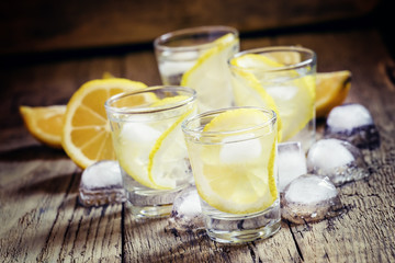 Lemon vodka with ice, vintage wooden background, selective focus