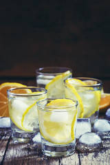 Lemon vodka with ice, vintage wooden background, selective focus
