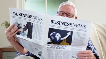 Senior man reading newspaper on couch - Powered by Adobe