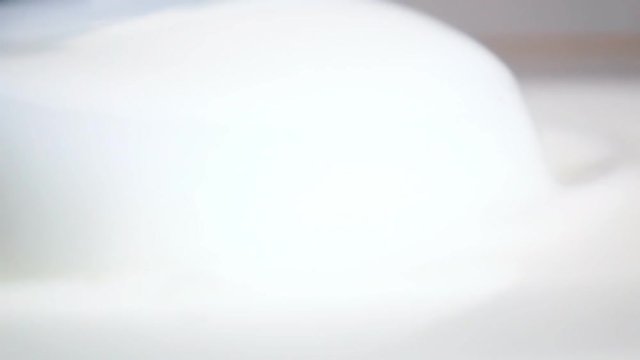Scooping up fresh white milk in big glass bowl with soup ladle. High speed shooting with slow motion camera.