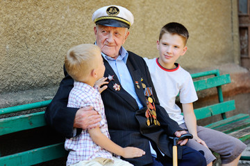 Obraz na płótnie Canvas WWII veteran with children. Grandchildren looking at grandfather