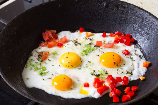 Fried egg, pepper, basil and onion on a pan