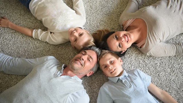 Upper view of family of 4 laying on carpet