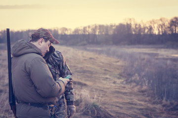Chasseurs dans les zones rurales pendant la saison de chasse tenant un smartphone et vérifiant leur emplacement via GPS