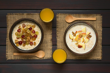 Oatmeal porridge with grapes, apples and walnuts in rustic bowls, glass of juice and wooden spoon...