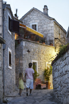 Brother and sister walking together through narrow street