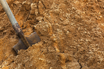 Construction shovel stuck in the sand. break during work