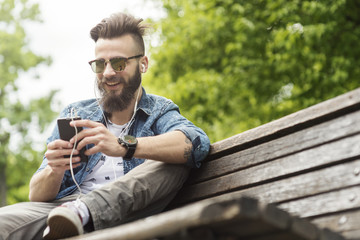 Young bearded fashionable man typing on cell phone