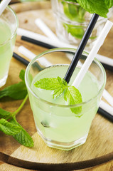 Green sweet cocktail with mint and ice on the wooden table