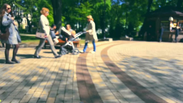People walk around the summer city park at sunny day, blurred background