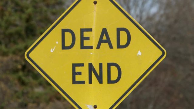 Tilt up and hold on a "Dead End" sign on a neighborhood street.
