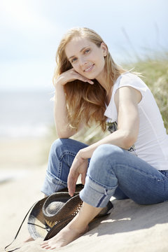 Young woman sitting on beach and looking at camera
