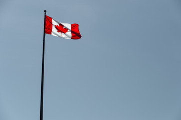 Canadian flag waving over pale blue sky
