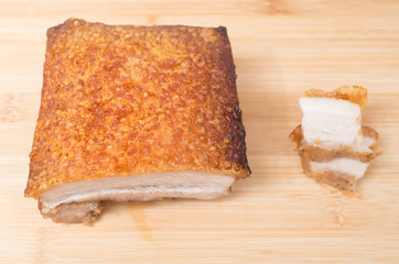 Close up view of a piece of Chinese roasted pork belly on wooden