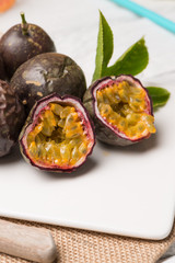 Passion fruits on white ceramic tray on wooden table background.