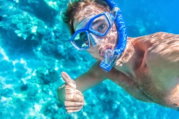 Fotobehang Snorkelen man onderwater duimen omhoog ok signaal dragen snorkel en masker plezier op strand zomervakantie vakantie genieten van recreatieve vrije tijd zwemmen in de zee. © Maridav