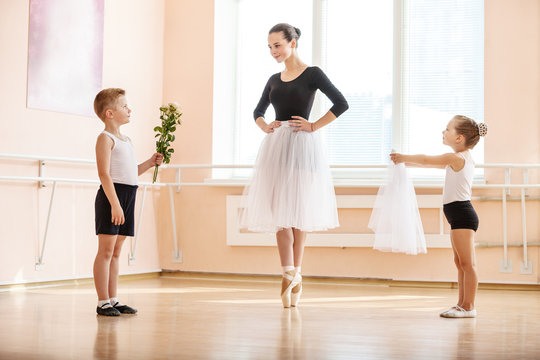 At ballet dancing class: young boy and girl giving flowers and veil to older student while she is dancing en pointe