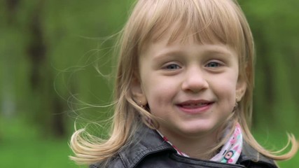 Portrait of 3 years old girl smiling on a camera. Slowly