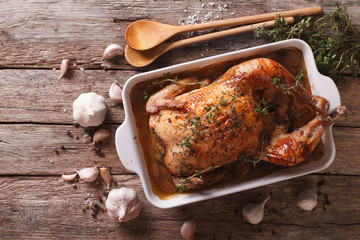 French Food: Chicken with 40 cloves of garlic in the dish for baking close-up. Horizontal top view  