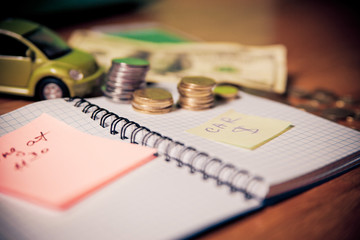 Notebook with records, counting money to pay car loan