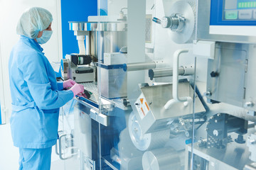Pharmaceutics. Pharmaceutical worker operates blister packaging machine  - obrazy, fototapety, plakaty