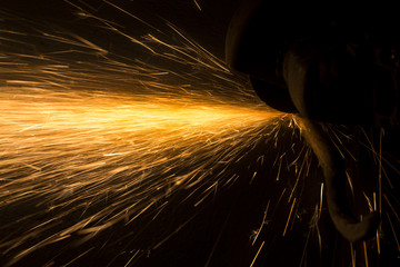 Glowing flow of steel metal spark particles shine in the dark background
