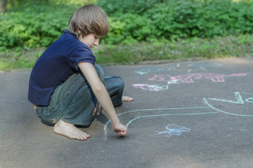 Sidewalk chalk drawings of barefoot teenage boy wearing blue t-shirt and jeans