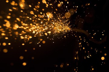 Glowing flow of steel metal spark particles and bokeh shine in the dark background