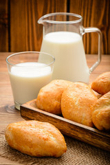Traditional  russian pastry piroshki and milk on wooden table.