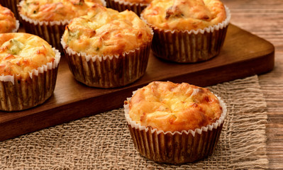 Homemade muffins with chicken and cheese on brown wooden board.