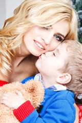 Portrait of beautiful blonde young woman with her little son over christmas background