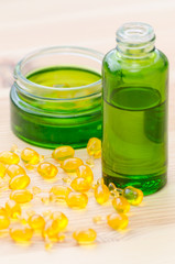 gold capsules with essential oils for face and green bottles on the wood