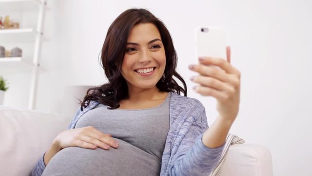 pregnant woman in smartphone video chat at home