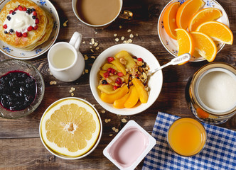 Breakfast pancakes, cereal, fruit and coffee on a wooden table.