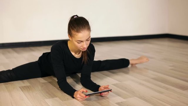 Flexible girl sitting on splits and reat tablet pc