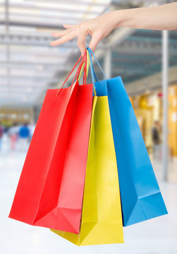 Woman hand holding shopping bags with shopping mall background