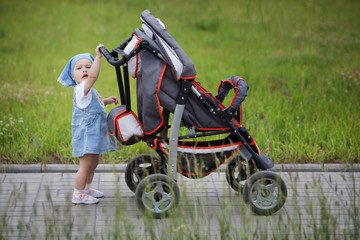 Obraz premium little funny girl with baby carriage