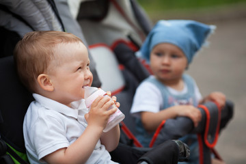 cute baby drinks juice sitting in baby carriage