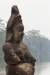 Guardian statue in South Gate of Angkor Thom temple, Cambodia. Trees background